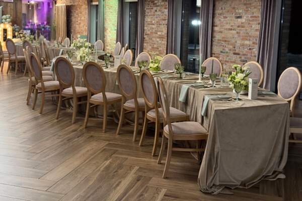 Sala z cegłą, drewnianym parkietem i serpentynymi stołami, Villa Mamma Nadarzyn